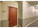 Neutral hallway with carpet and baseboards leading to unit 304 with a brown door at 4451 S Ammons St # 1-304, Littleton, CO 80123