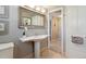 Well-lit bathroom featuring a pedestal sink, decorative mirror, and access to hallway at 1196 S Quebec Way, Denver, CO 80231