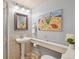 Well-lit bathroom features pedestal sink, decorative painting, and tiled shower, blending functionality with style at 1196 S Quebec Way, Denver, CO 80231