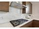 Close-up of modern gas cooktop with stainless steel range hood and subway tile backsplash at 2862 E 103Rd Ave, Denver, CO 80229
