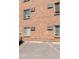 Close-up of a brick apartment building's exterior, with parking and windows at 155 S Pennsylvania St # 205, Denver, CO 80209