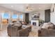 Inviting living room with a cozy fireplace, plush seating, and abundant natural light streaming through large windows at 244 Chipeta Way, Lochbuie, CO 80603