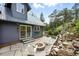 Backyard with a stone patio, fire pit, lush landscaping, and access to the house at 31 Wild Tiger Ln, Boulder, CO 80302