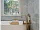 Close up of a soaking tub with elegant gold fixtures and natural light from the window at 31 Wild Tiger Ln, Boulder, CO 80302
