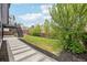 Landscaped backyard with green lawn, concrete paver pathway, and partial view of the home at 1057 English Sparrow Trl, Highlands Ranch, CO 80129
