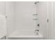 Clean bathroom with white tile, bathtub, and glass shelves at 1555 Perry St, Denver, CO 80204