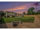 Large backyard with green grass, mature trees, patio, and gravel area with a bench during sunset at 6413 W 76Th Ave, Arvada, CO 80003