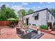 Backyard patio area with a cozy seating arrangement, including a sofa, chairs, and an umbrella at 1591 Holly St, Denver, CO 80220