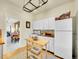 Bright kitchen featuring white appliances, kitchen island, and hardwood flooring with view to living room at 1256 S Pennsylvania St, Denver, CO 80210