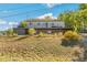 Home featuring an expansive outdoor deck with black metal railings, set against a lush hillside at 5385 W 51St Ave, Denver, CO 80212
