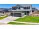 Two-story home featuring a three-car garage, stone accents, landscaped yard, and a well-maintained lawn at 9716 Uravan St, Commerce City, CO 80022