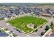 An aerial view of a park with a large green field, playground, and surrounding neighborhood streets at 9716 Uravan St, Commerce City, CO 80022