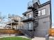 A modern-style residence features exterior metal stairs, a blue door, and gray siding at 3538 Pecos St, Denver, CO 80211