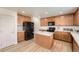 Well-designed kitchen with wood cabinets, black appliances, an island, and wood floors at 19431 E Wyoming Ave, Aurora, CO 80017