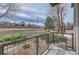 Apartment balcony overlooks beautiful landscaping with flower boxes, mature trees, and a brick wall in the distance at 5677 S Park Pl # B110, Greenwood Village, CO 80111