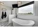 Spa-like bathroom featuring a soaking tub, large window, modern fixtures, and stylish tile flooring at 19185 Breton Pl, Monument, CO 80132