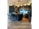 Modern kitchen featuring dark cabinetry, stainless steel appliances, a large island and wood-look floors at 653 Glenarbor Cir, Longmont, CO 80504