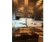 Kitchen sink area featuring granite counters, a stainless sink, designer tile and dark wood cabinets at 653 Glenarbor Cir, Longmont, CO 80504