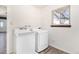 Clean laundry room features a modern washer and dryer set, natural light, and neutral walls at 7701 Hillgate Way, Parker, CO 80134