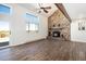 Bright living room features a stone fireplace, wood beam, large windows, and wood-look floors at 7701 Hillgate Way, Parker, CO 80134