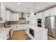 Bright, all-white kitchen features stainless appliances, herringbone backsplash, and a center island at 42984 Colonial Trl, Elizabeth, CO 80107