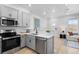 A modern kitchen boasts stainless steel appliances, gray cabinetry, and light wood flooring at 17152 W 91St Ln, Arvada, CO 80007