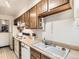 Galley kitchen featuring wood cabinets, white appliances, and double sink at 8236 Washington St # 29, Denver, CO 80229