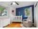 Bright bedroom featuring a white crib, changing table and chair with hardwood floors at 3200 Ames St, Wheat Ridge, CO 80212
