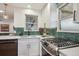 Updated kitchen features white cabinets, countertops, and green hexagon tile backsplash at 3200 Ames St, Wheat Ridge, CO 80212