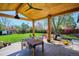 Covered patio with wooden ceiling and backyard featuring a swing, slide, and lush green space at 3200 Ames St, Wheat Ridge, CO 80212