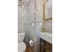 Elegant powder room with patterned wallpaper, a wall-mounted sink, and gold-tone fixtures at 3200 Ames St, Wheat Ridge, CO 80212