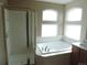 Bright bathroom with separate shower and soaking tub with tiled surround and window at 21024 E 49Th Ave, Denver, CO 80249