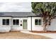 Charming white brick home with a manicured lawn, lush tree, and a welcoming green front door at 4023 E Martin Luther King Jr, Denver, CO 80207