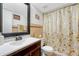 Cozy bathroom features a pedestal sink, vintage ceramic tiling, and shower with gold floral curtain at 364 S Ironton St # 425, Aurora, CO 80012