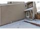 Home exterior showcasing tan siding, a side door with brick accents and a snow-covered lawn at 3719 S Ensenada St, Aurora, CO 80013