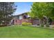 Charming home featuring a brick facade, lush lawn, and mature trees providing shade and curb appeal at 11621 Shoshone Way, Denver, CO 80234
