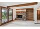 Basement living room featuring a stone fireplace, built-in bookshelves, beamed ceilings, and a sliding glass door at 11621 Shoshone Way, Denver, CO 80234