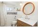 Modern bathroom features sleek vanity, round mirror, tub and updated fixtures at 6188 S Westview St, Littleton, CO 80120