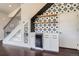 A built-in wet bar under the stairs featuring black and white patterned tile and open wood shelving at 3130 Hardin St, Castle Rock, CO 80109