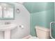 Small bathroom with pedestal sink, toilet, and light teal accent wall at 2728 Renshaw St, Strasburg, CO 80136