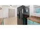 Black stainless steel refrigerator in a kitchen with teal cabinets at 2728 Renshaw St, Strasburg, CO 80136