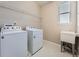 Bright laundry room featuring a Whirlpool washer and dryer set, utility sink, storage shelf, and neutral tones at 12953 Bridge View Ln, Parker, CO 80134