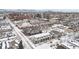 Aerial view of townhomes in snowy neighborhood with city skyline in background at 63 S Jackson St, Denver, CO 80209