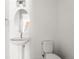 Simple bathroom with pedestal sink, toilet, and oval mirror at 63 S Jackson St, Denver, CO 80209