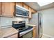 Kitchen featuring stainless steel appliances and wooden cabinets against neutral colored walls at 7845 Barbara Ann Dr # J, Arvada, CO 80004