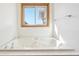 Window with a view above a soaking tub with white tile and wood trim at 20120 Doewood Dr, Monument, CO 80132
