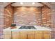 Close-up of a brick wall cooktop area in the kitchen with a white countertop and wood cabinets at 20120 Doewood Dr, Monument, CO 80132