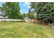 Large backyard with lush green grass, mature trees, privacy fence, and storage shed at 2013 S Holland St, Lakewood, CO 80227