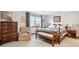 Comfortable bedroom with a queen-sized bed, wood furniture, and natural light from a bright window at 2013 S Holland St, Lakewood, CO 80227