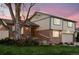 Charming two-story home with brick and siding exterior, lush landscaping, and a cozy front porch at 2013 S Holland St, Lakewood, CO 80227
